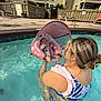 baby, baby_float, babywearing, child, floating, holding, inflatable_float, leisure, outdoor, person, pool, poolside, relaxation, residential_building, summer, sunshade, swimsuit, water, water_activity, woman