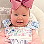 baby, child, smiling, pink_bow, floral_dress, daddys_girl, cushioned_chair, infant, cute, happy, portrait, indoors, headband, person, baby_clothes, baby_girl, close_up, cheerful, seated, plush