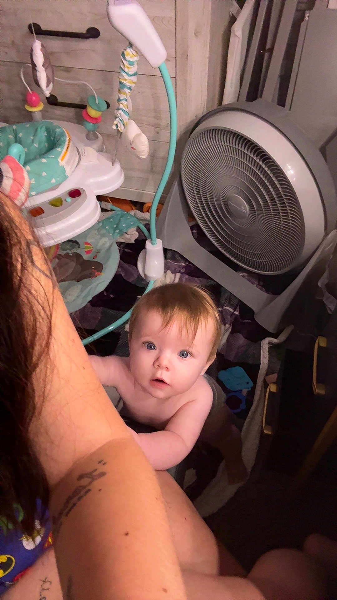 Lorelai is registered to the contest to win money with this photo: arm, baby, baby_gear, blanket, blue_eyes, child, curious, fan, floor, hair, holding, household_item, indoor, light, looking_up, person, room, skin, tattoo, toy
