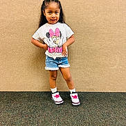 Eulalia is registered to the contest to win money with this photo: child, girl, portrait, standing, smiling, posing, indoors, fashion, clothing, t_shirt, shorts, sneakers, socks, minnie_mouse, cartoon, long_hair, braids, carpet, wall, full_body