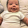 baby, infant, smile, white_onesie, chubby_cheeks, lying_down, blanket, soft_texture, cute, happy, person, indoors, child, face, head, skin, hair, expression, newborn, closeup