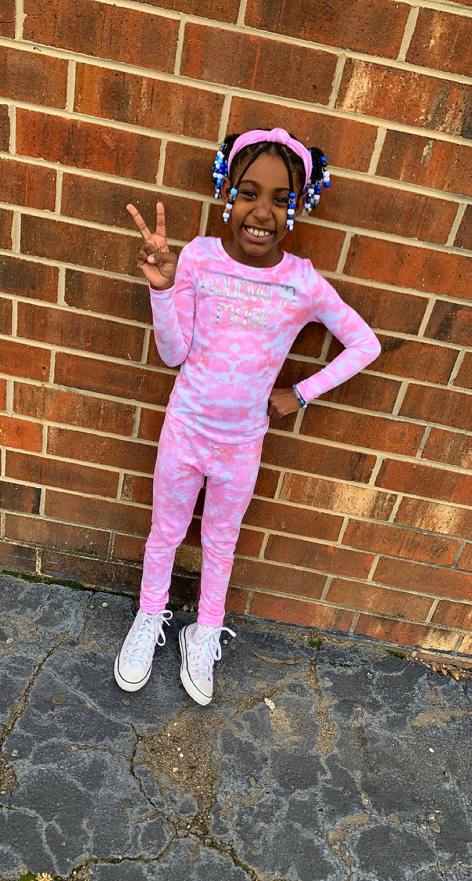 Izzy is registered to the contest to win money with this photo: brick, brickwork, cap, child, cool, eyewear, fun, happy, headgear, joy, magenta, pattern, person, personal_protective_equipment, pink, purple, shoe, sleeve, smile, street_fashion