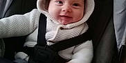 Reginald is registered to the contest to win money with this photo: baby, baby_clothes, baby_face, child, cozy, cute, happy, headwear, hoodie, indoor, infant, knitted, person, portrait, seatbelt, sitting, smile, stroller, white_clothing, young_child