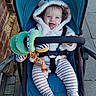 Reginald joined the competition — help win amazing prizes! baby, stroller, toy, giraffe_toy, hooded_jacket, striped_pajamas, outdoor, sidewalk, brick_wall, happy, child, infant, smiling, seatbelt, footwear, playful, cute, blue, green, person