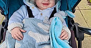 Reginald joined the competition — help win amazing prizes! baby, child, stroller, blanket, hooded_jacket, smiling, outdoor, pavement, toy, plush_bunny, cozy, cute, happy, infant, person, clothing, blue, warm, portrait, seated