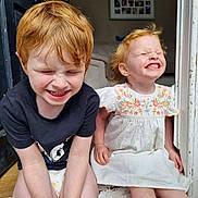 Veronica-Rose joined the competition — help win amazing prizes! child, children, red_hair, smiling, sitting, doorway, diaper, dress, embroidered, indoor, happy, cute, siblings, funny_face, playful, person, two_people, light, hair, grin