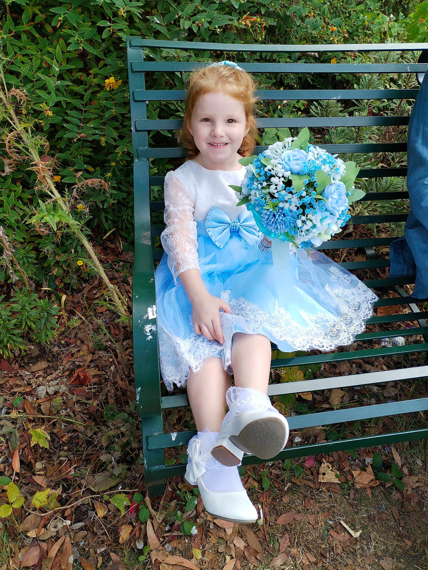 Veronica-Rose is registered to the contest to win money with this photo: child, girl, smiling, blue_dress, white_shoes, flower_bouquet, bench, outdoor, greenery, plants, leaves, happy, portrait, sitting, nature, dress, cute, young_child, garden, footwear