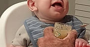 Carson joined the competition — help win amazing prizes! adult_hand, baby, bib, child, clothing, face, feeding, food_jar, furniture, happy, high_chair, home, indoor, mealtime, person, portrait, smiling, spoon, tattoo, watch