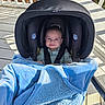 baby, blanket, blue_blanket, car_seat, child, clothing, cozy, cute, happy, infant, infant_face, outdoor, person, porch, seatbelt, shadows, smile, sunlight, white_railing, wooden_floor