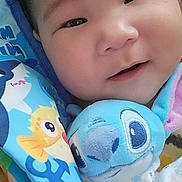 Ariimoana a rejoint le concours — aidez-le/la à gagner de superbes lots ! baby, smiling, face, plush_toy, blue, yellow, pink, cozy, infant, cute, portrait, child, soft, happy, indoors, blanket, stuffed_animal, colorful, closeup, adorable