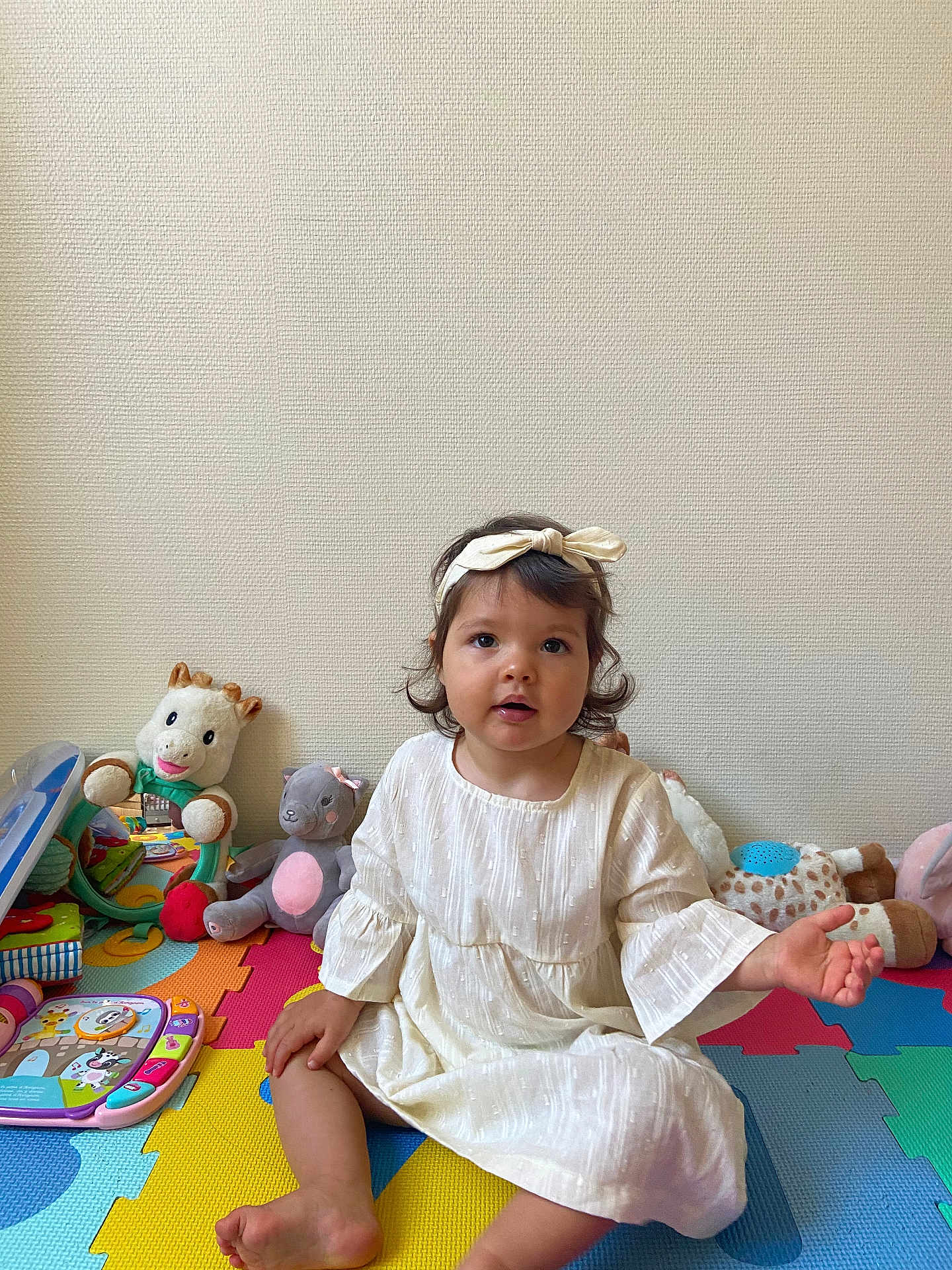Lorianna participe au concours pour gagner de l'argent avec cette photo : child, toddler, dress, headband, toy, plush_toy, play_mat, indoor, colorful, floor, cute, sitting, person, young_child, educational_toy, smiling, happy, baby, girl, soft_toy