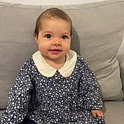 Lorianna a rejoint le concours — aidez-le/la à gagner de superbes lots ! baby, child, girl, sitting, couch, gray_couch, floral_dress, white_collar, socks, polka_dot, indoors, cute, smiling, young_child, person, portrait, happy, comfortable, home, furniture