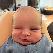 Remi is registered to the contest to win money with this photo: baby, blue_clothing, chubby_cheeks, closeup, cozy, cute, expression, face, head, human, indoors, infant, lap, person, portrait, resting, skin, smile, winking, young_child