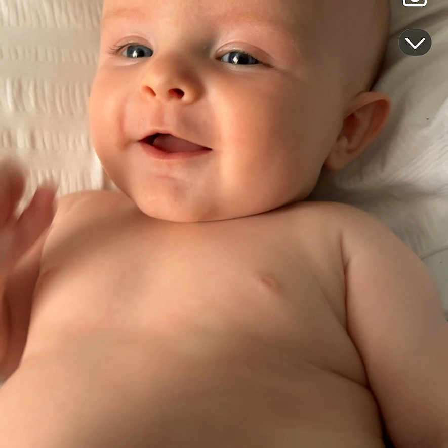 Remi is registered to the contest to win money with this photo: baby, blanket, child, close_up, cute, eyes, face, hand, happy, head, indoors, infant, lying_down, mouth, natural_light, portrait, skin, smiling, texture, young