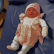 Cora is registered to the contest to win money with this photo: baby, infant, pink, lace, hat, clothing, cushion, blue, soft, cute, indoor, person, newborn, footwear, gloves, lying_down, portrait, adorable, fabric, warm