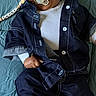 baby, denim, clothing, pacifier, smile, child, lying_down, quilt, blue, white_shoes, beads, name_tag, cute, happy, infant, person, face, casual, relaxed, indoors