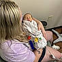 newborn, baby, woman, hospital, medical_equipment, blanket, tattoo, chair, indoor, caring, person, healthcare, resting, striped_blanket, casual_clothing, female, tubes, floor, wall, footwear