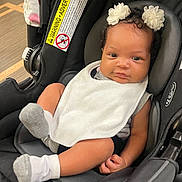 Lavender joined the competition — help win amazing prizes! baby, infant, car_seat, bib, socks, curly_hair, flower_headbands, black_car_seat, child, indoor, portrait, cute, smile, small_hands, white_bib, cozy, seated, looking_at_camera, skin, headwear