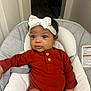 Lavender is registered to the contest to win money with this photo: baby, infant, headband, bow, onesie, red_clothing, cushion, baby_seat, indoor, person, child, cute, wide_eyes, comfortable, expression, small_hands, soft_fabric, home, seatbelt, portrait