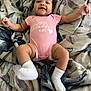 baby, infant, smile, pink_onesie, bow, lying_down, blanket, happy, cute, child, sock, patterned_blanket, toddler, face, skin, small_child, indoors, portrait, person, young