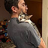 brown_fur, cat, doorway, feline, glasses, green_eyes, holding, home, indoors, kitchen, man, person, pet, portrait, profile, short_hair, shoulder, tabby, whiskers, white_fur