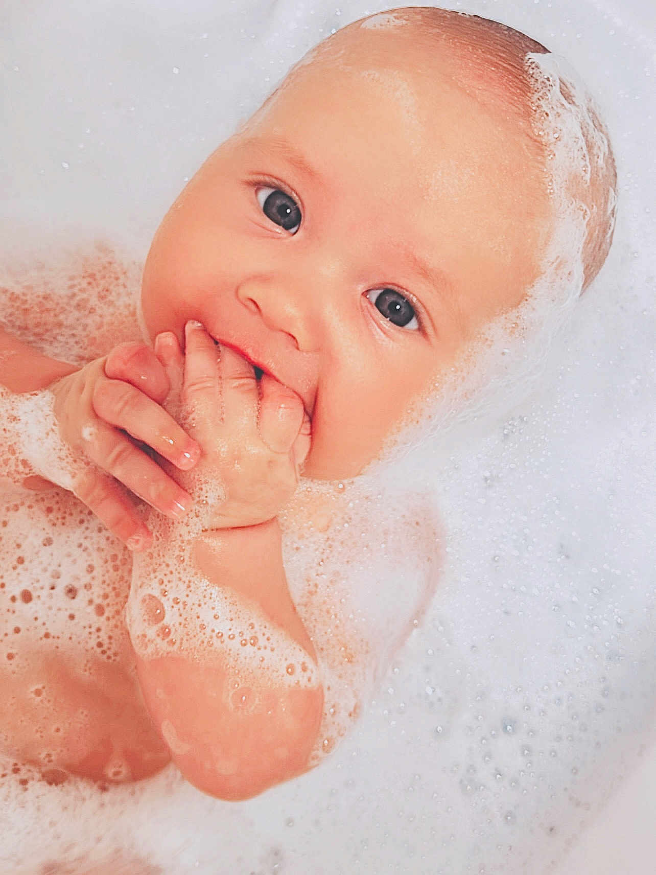 Sophia is registered to the contest to win money with this photo: baby, bathtub, bubbles, foam, water, child, skin, hands, face, eyes, cute, wet, infant, bath, cleaning, soapy, relaxation, young, portrait, playful