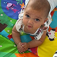 Léna participe au concours pour gagner de l'argent avec cette photo : baby, infant, child, play_mat, colorful, animal_prints, toddler, clothing, hands, face, looking_up, eyes, cute, indoor, floor, pattern, skin, expression, lying_down, young