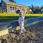 Harmony joined the competition — help win amazing prizes! toddler, child, outdoor, sunny, wood_chips, grass, house, building, blue_sky, shadow, clothing, sneakers, hoodie, expression, nature, daylight, playground, person, young_child, smiling