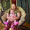 Sophia joined the competition — help win amazing prizes! baby, woman, smiling, hanging_chair, indoor, patterned_pants, pink_socks, happy, seated, wooden_floor, tattoo, long_hair, comfort, casual_clothing, parent_and_child, relaxation, candid, portrait, natural_light, home