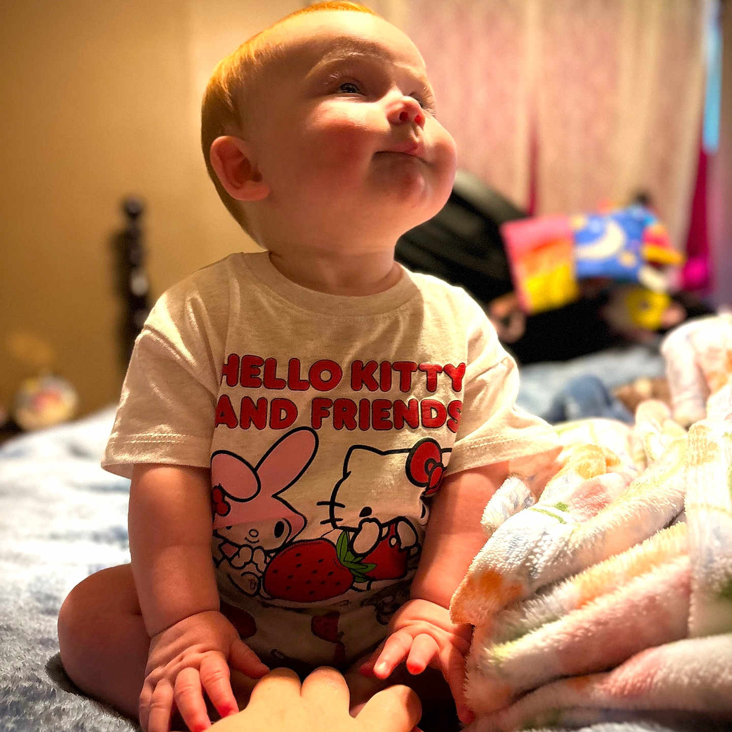 Sophia is registered to the contest to win money with this photo: baby, child, infant, hello_kitty, shirt, hand, bed, blanket, indoor, person, cute, sitting, cozy, soft, plush, furniture, face, expression, skin, young