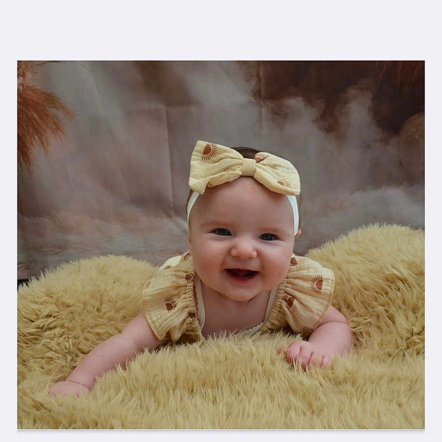 Khatalia a rejoint le concours — aidez-le/la à gagner de superbes lots ! baby, blanket, bow, child, clothing, cozy, cute, face, fluffy, happy, headband, indoors, infant, lying_down, person, portrait, smiling, soft_texture, yellow, young