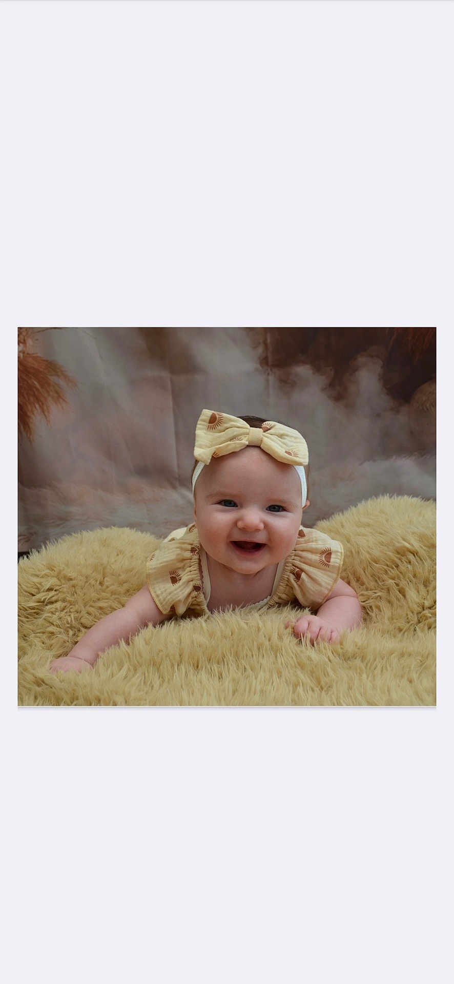 Khatalia a rejoint le concours — aidez-le/la à gagner de superbes lots ! baby, smiling, headband, bow, blanket, fluffy, infant, cute, happy, portrait, child, soft_texture, yellow, clothing, lying_down, indoors, face, person, young, cozy