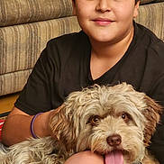 Lilly is registered to the contest to win money with this photo: boy, dog, indoor, couch, smiling, pet, fur, happy, child, casual, portrait, home, brown_hair, black_shirt, playful, tongue_out, seated, friendly, cozy, relaxed