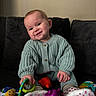Isla is registered to the contest to win money with this photo: baby, child, smiling, knitted_sweater, toys, couch, indoor, cute, happy, playtime, person, footwear, purple_toy, red_toy, colorful, soft_furniture, portrait, infant, sitting, cozy