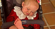 Isla joined the competition — help win amazing prizes! baby, barefoot, blonde_hair, child, cozy, cute, harness, indoor, infant, lace_collar, peaceful, pink_bow, portrait, raised_foot, red_outfit, seated, sleeping, stroller, tiled_floor, wheelchair_like_stroller