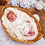 baby, sleeping, wicker_basket, blanket, wooden_floor, plush_toy, teddy_bear, headband, skirt, long_sleeve_shirt, infant, soft_texture, cozy, cute, indoors, floor_rug, peaceful, resting, newborn, portrait