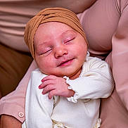 Sofia a rejoint le concours — aidez-le/la à gagner de superbes lots ! adult_arm, baby, closeup, comfort, cozy, cute, fabric, family, hand, headwrap, human, infant, peaceful, portrait, skin, sleeping, smile, soft_lighting, warm_colors, white_clothing