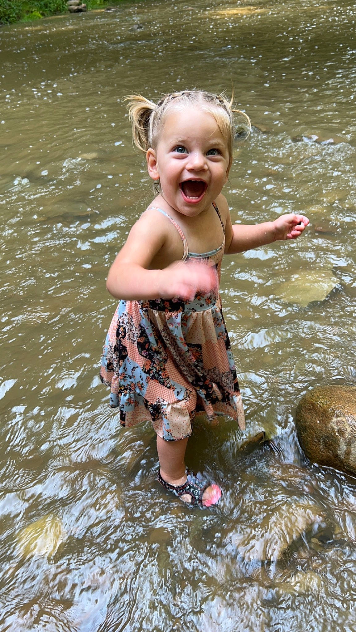 Elouise is registered to the contest to win money with this photo: baby_toddler_clothing, barefoot, bathing, child, face, fun, grass, happy, head, lake, leisure, pattern, people_in_nature, person, play, recreation, smile, stream, swimwear, toddler
