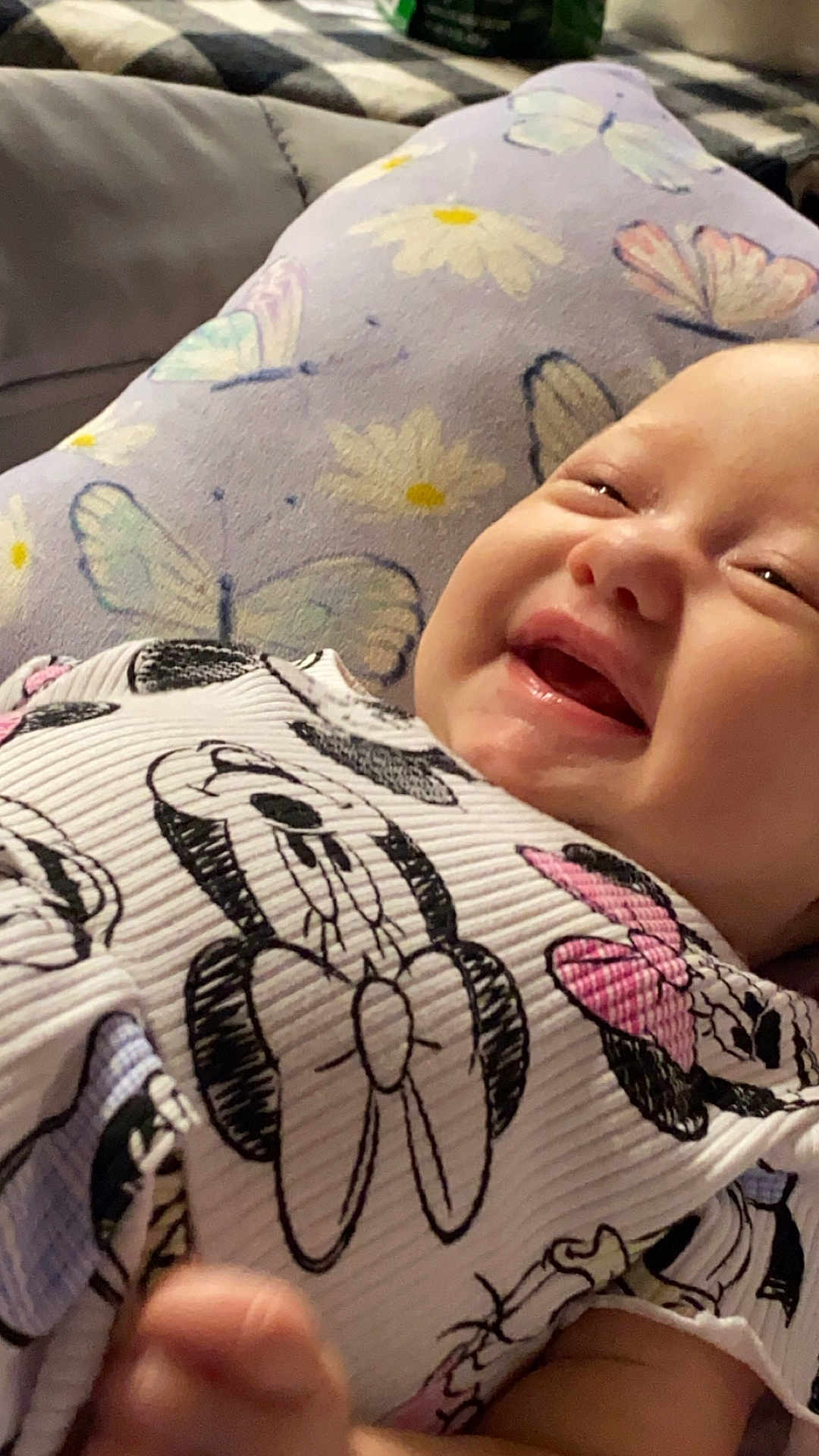 Allison is registered to the contest to win money with this photo: apparel, baby, butterfly, cartoon, child, closeup, clothing, cute, fabric, face, happy, infant, lying_down, pattern, person, pillow, portrait, skin, smiling, soft_lighting