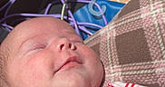 Lainie joined the competition — help win amazing prizes! baby, smile, sleeping, face, infant, striped_clothing, strawberry_patch, blanket, plaid_pattern, soft_light, child, peaceful, cute, indoors, newborn, head, hand, resting, cozy, portrait