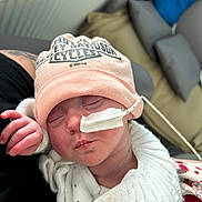 Eleanor a rejoint le concours — aidez-le/la à gagner de superbes lots ! baby, newborn, infant, hat, beanie, feeding_tube, medical_tape, sleeping, swaddle, knitwear, hand, face, closed_eyes, mouth, nose, cushion, sofa, pillow, caregiver_arm, cozy