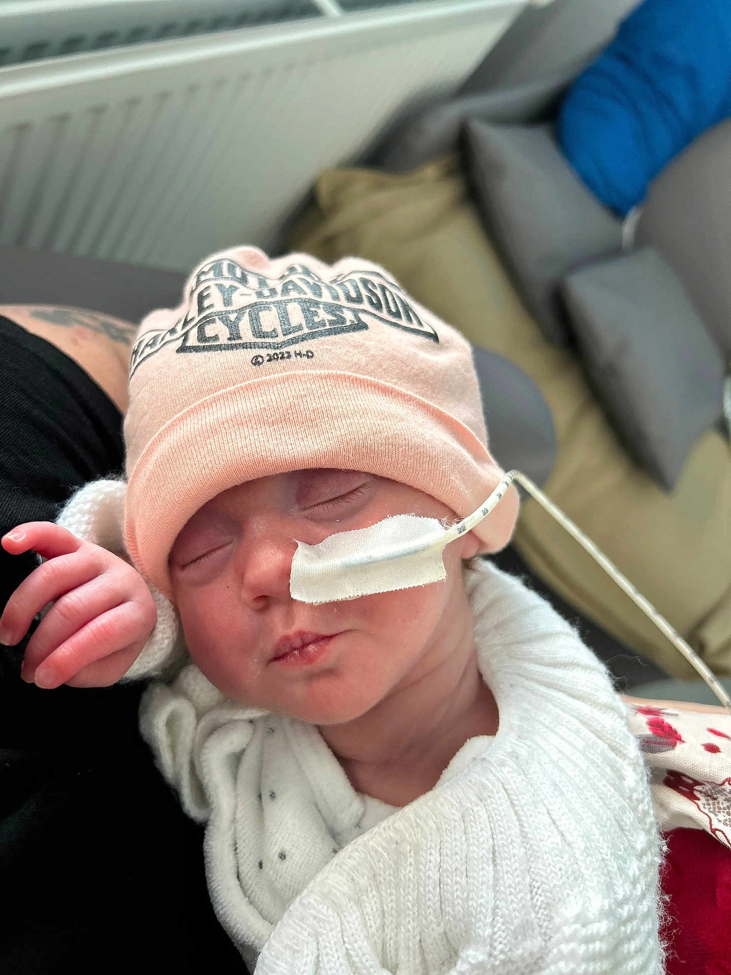 Eleanor a rejoint le concours — aidez-le/la à gagner de superbes lots ! baby, newborn, infant, hat, beanie, feeding_tube, medical_tape, sleeping, swaddle, knitwear, hand, face, closed_eyes, mouth, nose, cushion, sofa, pillow, caregiver_arm, cozy