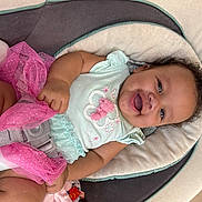 Kollyns is registered to the contest to win money with this photo: baby, infant, smiling, mint_clothing, pink_tutu, car_seat, buckle, harness, toy, cushion, portrait, close_up, happy, chubby_cheeks, curly_hair, hand, fabric, indoor, seat, playful