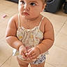 Amy Albert Sosa is registered to the contest to win money with this photo: toddler, child, indoors, barefoot, tile_floor, couch, hair_buns, curious, holding, casual_clothing, necklace, living_room, cute, young_child, person, floor, furniture, expression, skin, portrait