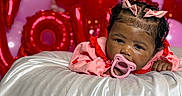 Kalani is registered to the contest to win money with this photo: baby, pacifier, pink_bows, red_balloons, pink_balloons, love_balloons, silky_fabric, infant, child, portrait, celebration, cute, lying_down, decorations, indoor, closeup, face, expression, holiday, festive