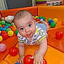 baby, child, ball_pit, colorful, play_area, orange_cushion, plastic_balls, crawling, cute, indoor, toddler, fun, childcare, playtime, smiling, curious, small_hand, bright_colors, soft_padded, infant