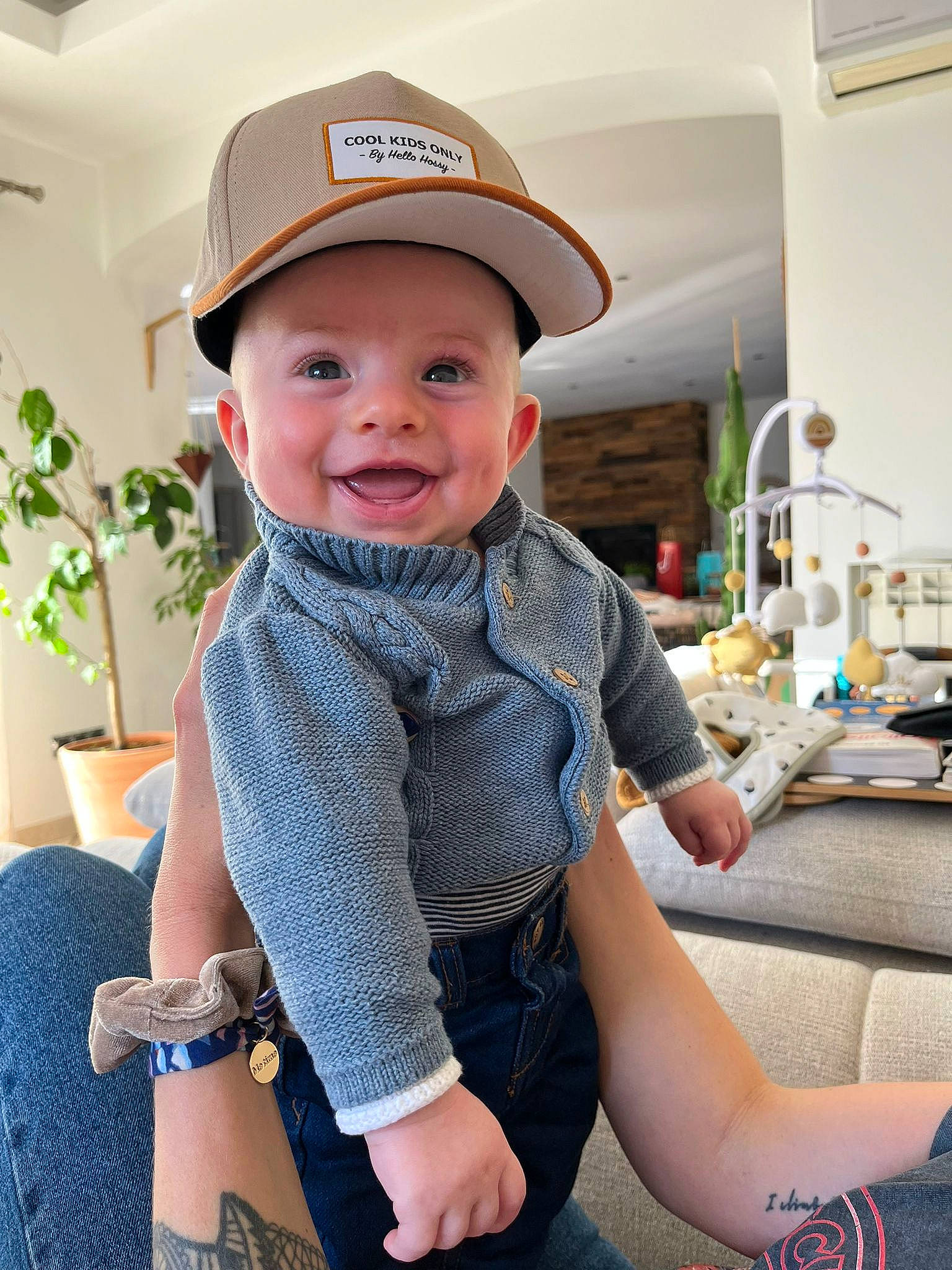 Valentin a rejoint le concours — aidez-le/la à gagner de superbes lots ! baby, baby_toddler_clothing, baseball_cap, cap, child, comfort, flowerpot, fun, happy, headwear, houseplant, joy, knee, lap, person, plant, skin, sleeve, smile, standing