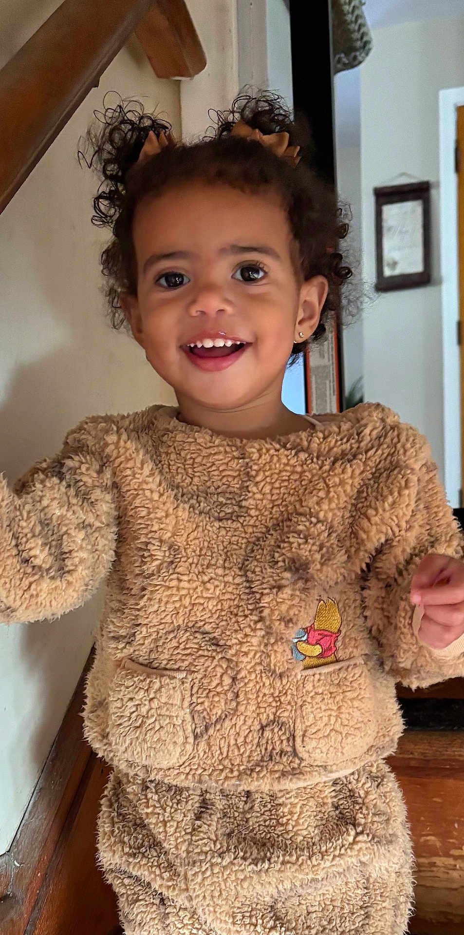 Peyton joined the competition — help win amazing prizes! toddler, child, smiling, curly_hair, pigtails, cozy_clothing, fuzzy_outfit, beige, indoor, home, happy, portrait, cute, earrings, embroidered_character, pocket, standing, wood_floor, wall, door