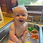Levi is registered to the contest to win money with this photo: baby, child, sink, water, bath, toys, rubber_duck, kitchen, window, smile, happy, play, toddler, indoor, cute, person, plastic_toys, water_bubbles, daylight, faucet