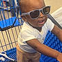 baby, child, sunglasses, shopping_cart, store, aisle, person, standing, clothing, pants, white_shirt, blue, floor, earrings, smiling, cute, indoor, retail, shopping, accessory